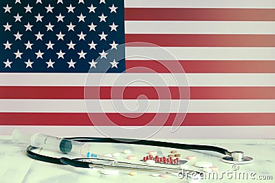 USA flag on the background of tablets, stethoscope and medical syringe on the table. American flag and medical supplies Stock Photo