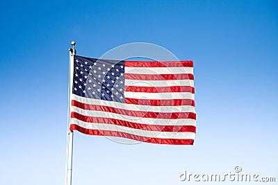 USA flag waving in the wind against blue sky on a sunny day Stock Photo