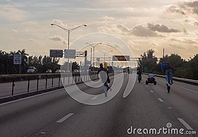 Bike riders drive recklessly on road in front of sign that reads don`t text and drive Editorial Stock Photo