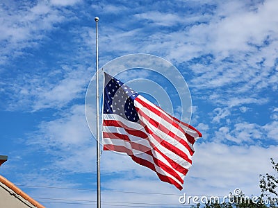 USA national flag waving lowered to half mast on wind against blue sky. American stars and stripes spangled banner as Stock Photo