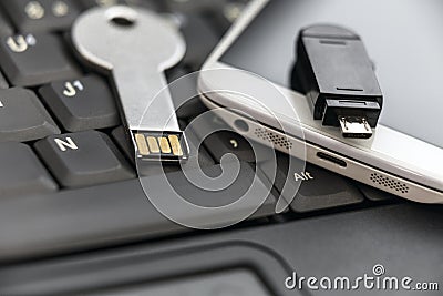 USB key and smartphone with micro USB flash drive on laptop keyboard Stock Photo