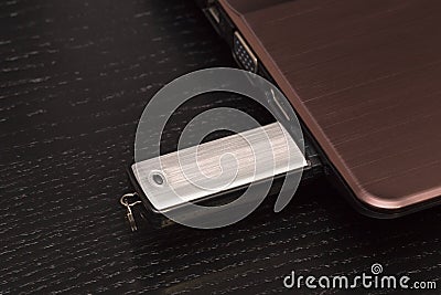 USB metal flash drive connected by hand to a laptop Stock Photo