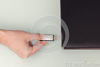 USB metal flash memory on hand with notebook computer connected Stock Photo