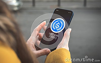 USD coin USDT cryptocurrency symbol, logo. Business and financial concept. Hand with smartphone, screen with crypto icon Editorial Stock Photo