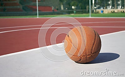 Used basketball in the foreground lies on an empty basketball court with a blurred background Stock Photo