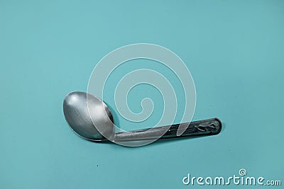 A used and bent spoon, isolated on a blue background. Stock Photo