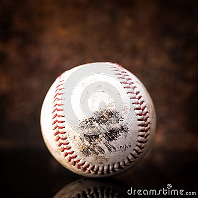 Used dirty Baseball in front of brown background Stock Photo