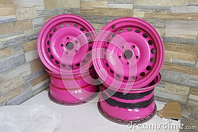 Used Metal stamped rims for cars. Custom made pink steel wheels on the stone wall background Stock Photo