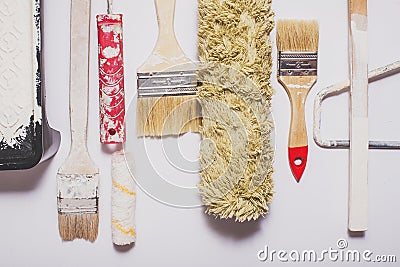 Used painting tools with red handles covered in warm white paint Stock Photo