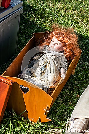 Used red-hair doll in wooden cradle at charity sale Stock Photo