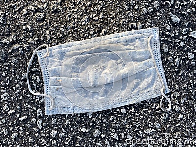 Used surgical mask smashed by traffic in a parking lot Stock Photo