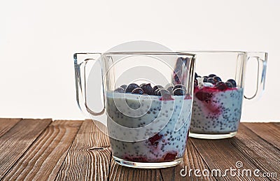 Useful and nourishing breakfast, pudding of currant berries, cherries with yoghurt and chia seeds in glass cups on wooden backgrou Stock Photo