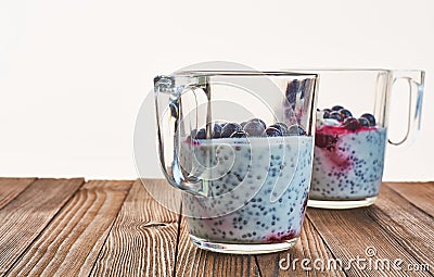 Useful and nourishing breakfast, pudding of currant berries, cherries with yoghurt and chia seeds in glass cups on wooden backgrou Stock Photo