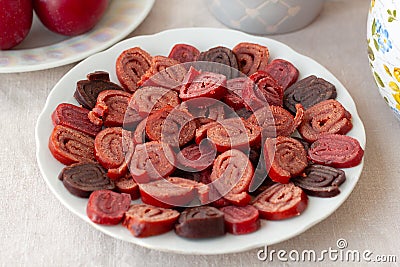 Useful sweets fruit paste is on a plate next to the plums a Cup and a teapot Stock Photo