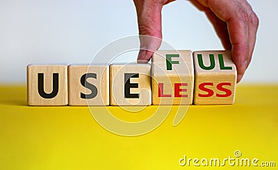 Useful or useless symbol. Male hand turns cubes and changes the word `useless` to `useful`. Beautiful yellow table, white Stock Photo