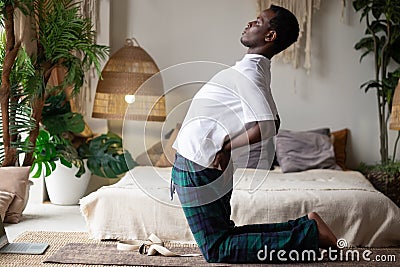 Yoga ushtrasana camel pose by african man at home. Stock Photo
