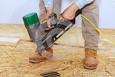 Using an air nail gun to install wooden plywood on floor of a new house Stock Photo