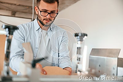 Using the cutting machine. Print house worker in white clothes is indoors Stock Photo
