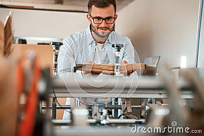 Using the cutting machine. Print house worker in white clothes is indoors Stock Photo