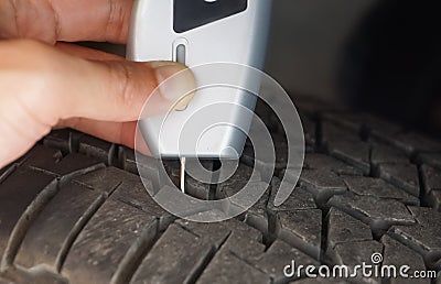 Using a digital tire tread depth measuring tool with old tire Stock Photo