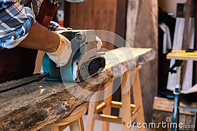 Using sanding machine belt sander to level surface wood. Carpenter use a hand-held electric sanding machine in carpentry workshop Stock Photo