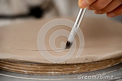 Using a sharp pottery carving knife to cut out a perfect round shape from clay. Ceramics class. Modeling clay into a Stock Photo