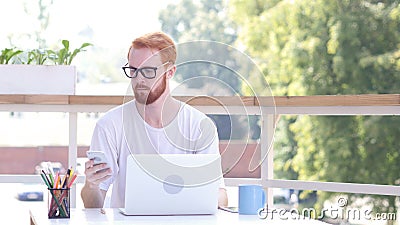 Using Smartphone, Sitting in utdoor Office, Red Hairs Stock Photo