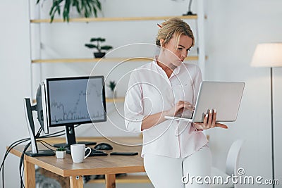 Using smartphone to communicate. Female stock broker in formal wear is working in the office Stock Photo