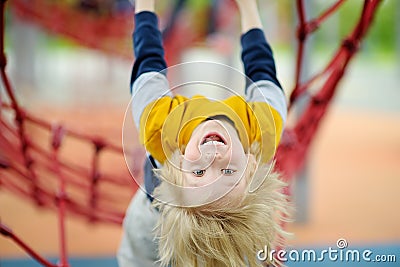 Ð¡ute perky preschooler boy having fun on outdoor playground. Spring/summer/autumn active sport leisure for kids. Outdoor Stock Photo