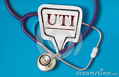 UTI - acronym on white figure sheet on a blue background with a stethoscope Stock Photo