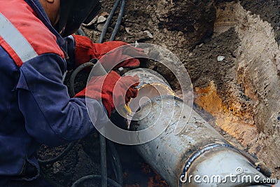 Utility worker fixing broken water main. Sewerage pipe repair concept. Stock Photo