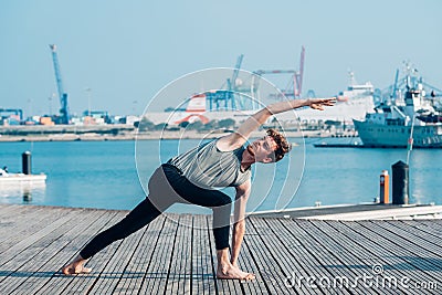 Utthita Parsvakonasana is a complicated yoga posture that stretches the trunk muscles, practiced by a man Stock Photo