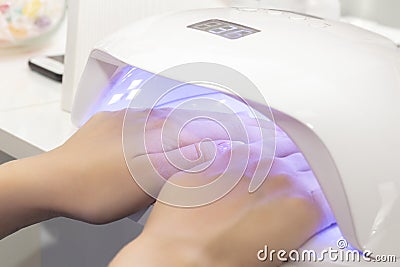 UV lamp for drying varnish for two hands. girl dries shellac on two hands in lamp Stock Photo