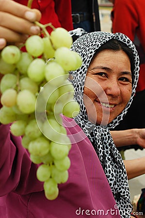 Uyghur woman selling grapes at market Editorial Stock Photo