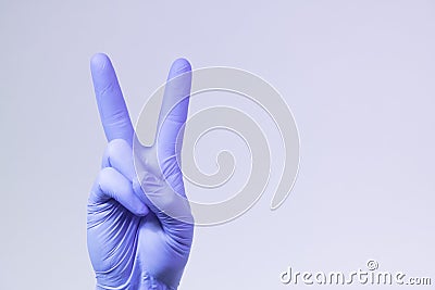 V sign is showed by right man hand in a purple medical glove on a white background. Victory over a virus Stock Photo