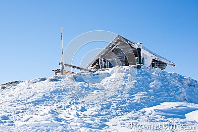 Vacation rural winter background. Small wooden alpine house covered with snow Stock Photo