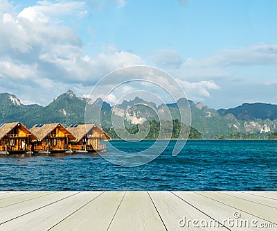 Vacation Start Here Concept, Wooden Perspective Floor with Beautiful Wooden Floating House in Peaceful View of Ratchaprapa dam Stock Photo