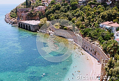Vacationers bathe and sunbathe against the background of the ancient fortress wall Alanya, Turkey Editorial Stock Photo