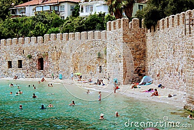 Vacationers bathe and sunbathe against the background of the ancient fortress wall Alanya, Turkey Editorial Stock Photo