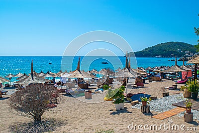 Vacationers on beautiful clean sand and pebble beach with umbrellas and sun loungers. Sunny mountains blue seaside landscape. Editorial Stock Photo