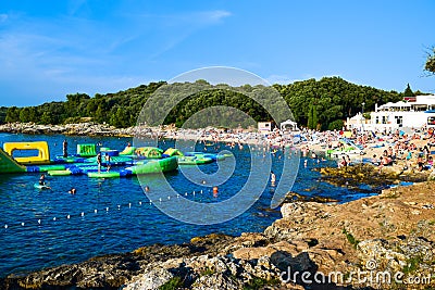 Vacationers on the free stony and pebble Ambrela beach of the Adriatic Sea on a summer sunny day. Pula, Croatia Editorial Stock Photo