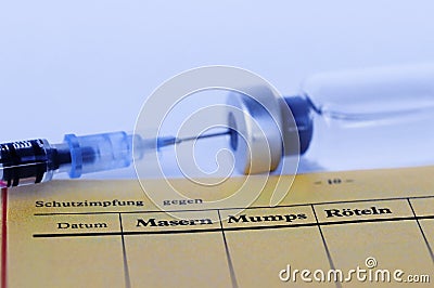 Vaccination against measles, mumps and rubella with vaccination card, syringe and vaccine Stock Photo