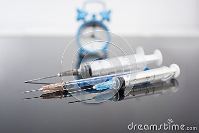 Vaccination time. Vaccine in vial with syringe on clock background. Prevention immunization illness Stock Photo