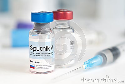 The vaccine sputnik V from the coronovirus infection covid 19 on a blue background and a syringe on the table Editorial Stock Photo