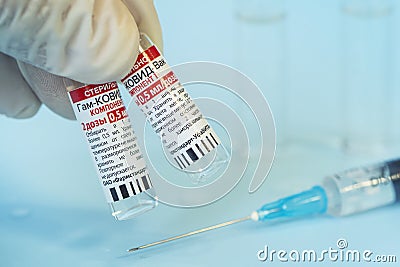 The vaccine sputnik V from the coronovirus infection covid 19 on a blue background and a syringe on the table Editorial Stock Photo