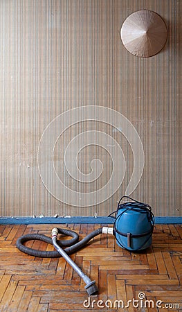 Vacuum cleaner is on parquet floor. Hat hangs on the wall Stock Photo