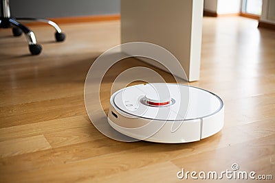 Vacuum cleaner robot runs on wood floor in a office Stock Photo