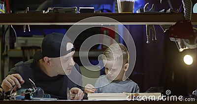 Vader leert kleine jongen om hamernagels te gebruiken en boor samen in een workshop een vader - en zoontconcept stock videobeelden Vader leert kleine jongen om hamernagels te gebruiken en boor samen in een workshop een vader - en zoontconcept stock videobeelden