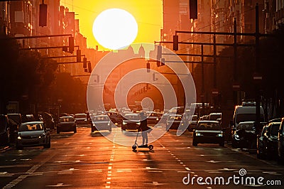 Valencia port avenue, giant sun during sunset, silhouette of man on electric scooter and cars Stock Photo