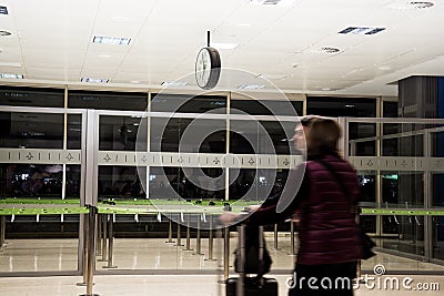 Valencia, Spain - December 13, 2019 - Defocused people walking inside the airport. Clock on the ceiling of the room Editorial Stock Photo